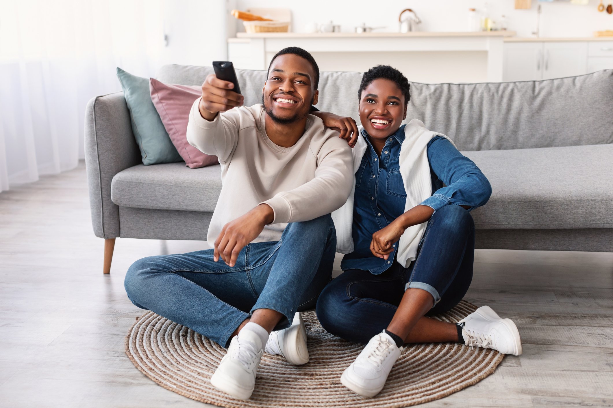 Two people sitting on the floor watching television.