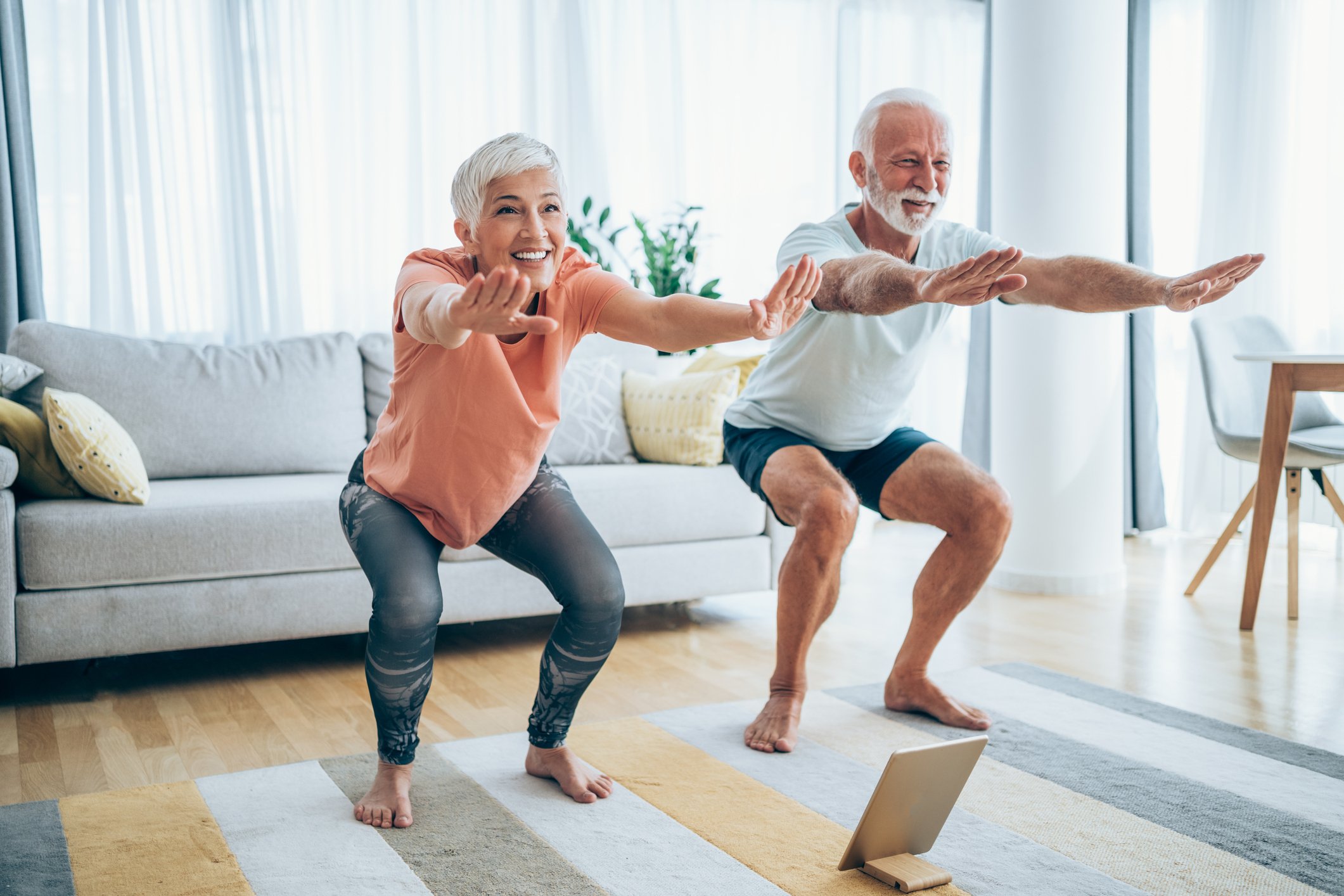 An older couple practicing yoga at home.
