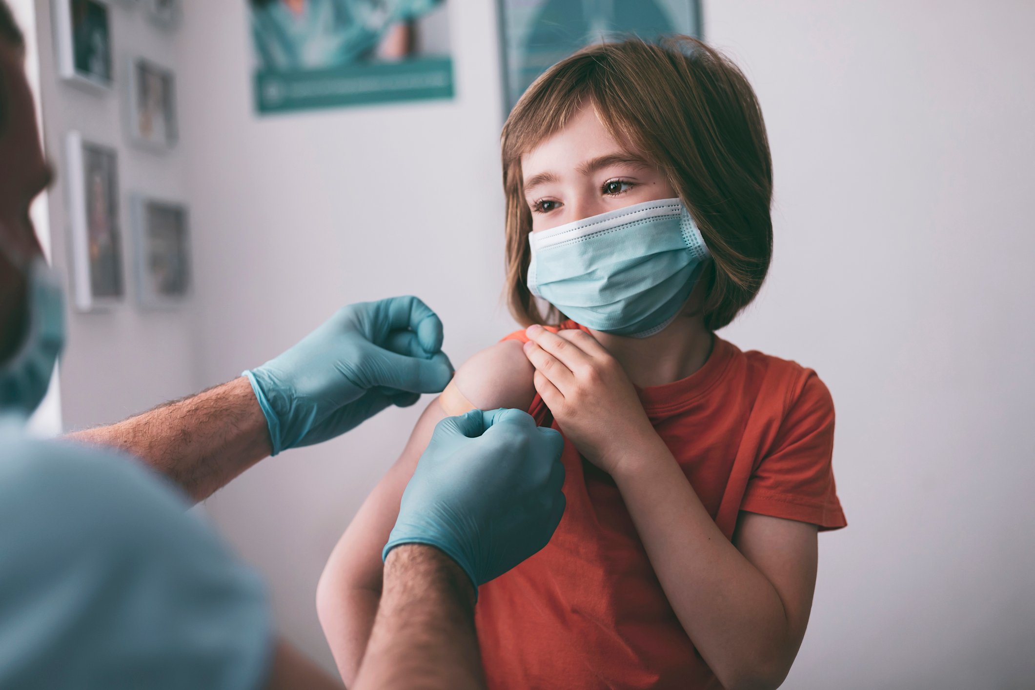 Young child in a mask receives a vaccine. 