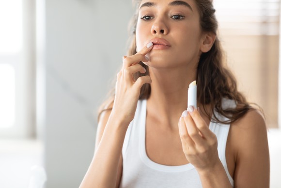 Person applying a lip care product to their face.