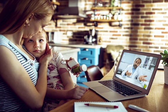 Adult and child participating in a telehealth session with a medical professional.