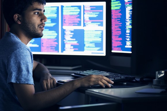A person works with code in front of large monitors. 