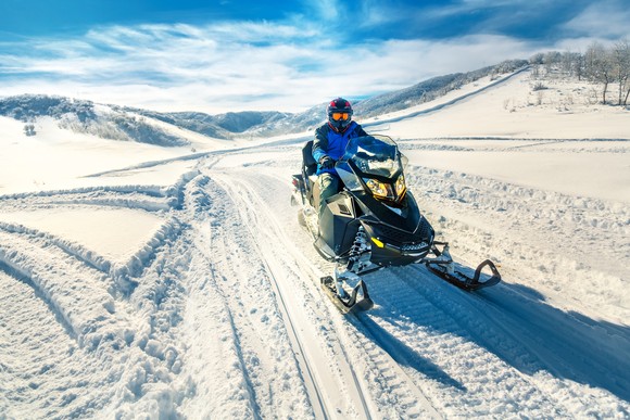 Person on snowmobile in winter landscape.