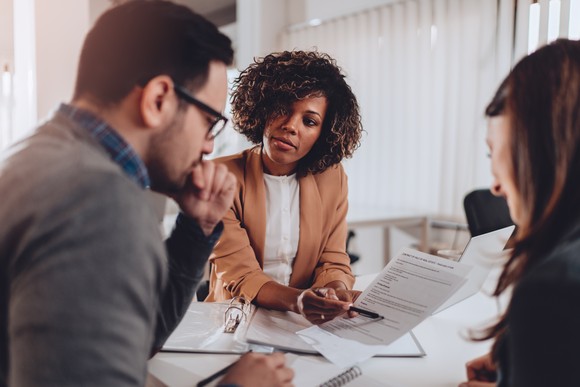 A real estate agent is showing documents to her clients. 