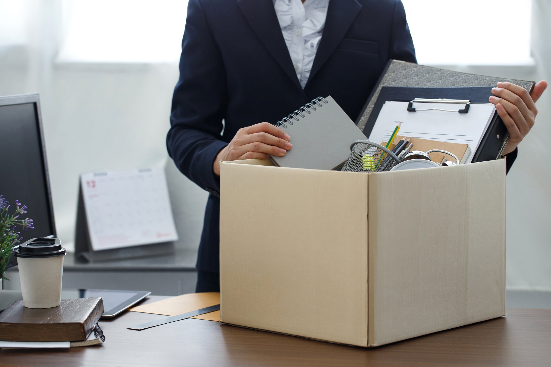 Person in an office packing belongings into a cardboard box.