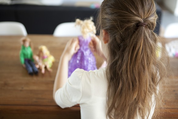A child playing dress-up with dolls.