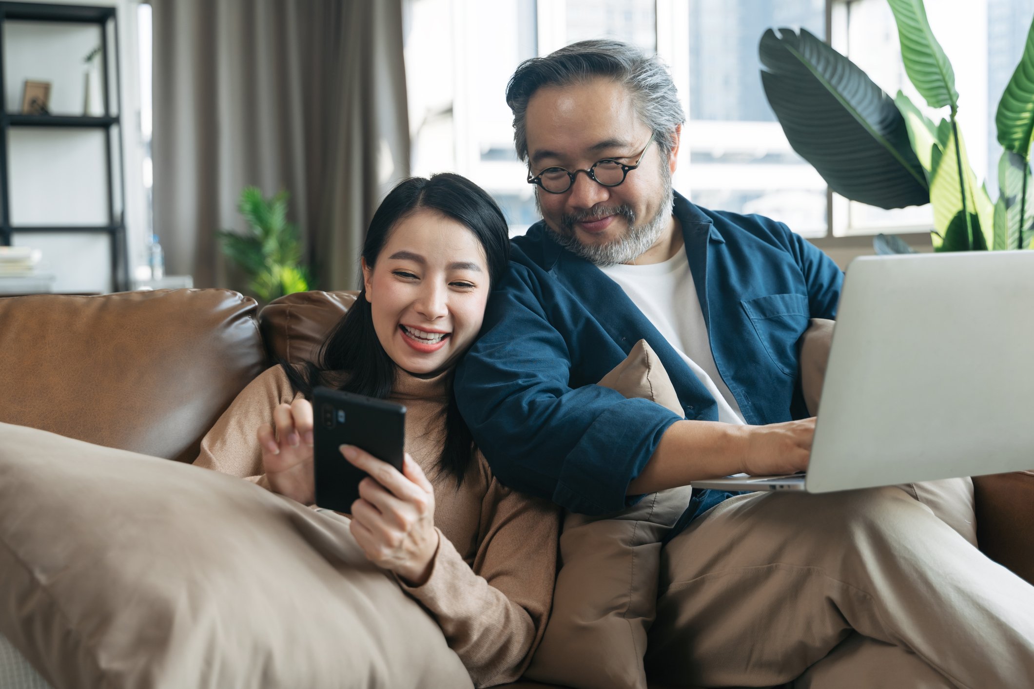 Two people with laptop and smartphone sitting on a couch together.