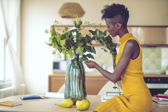 A person putting flowers in vase on a table. 