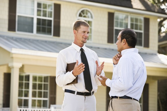 Two people having discussion outside a house.