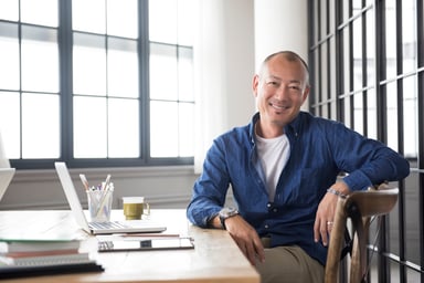 A smiling person at a desk_GettyImages-475566446