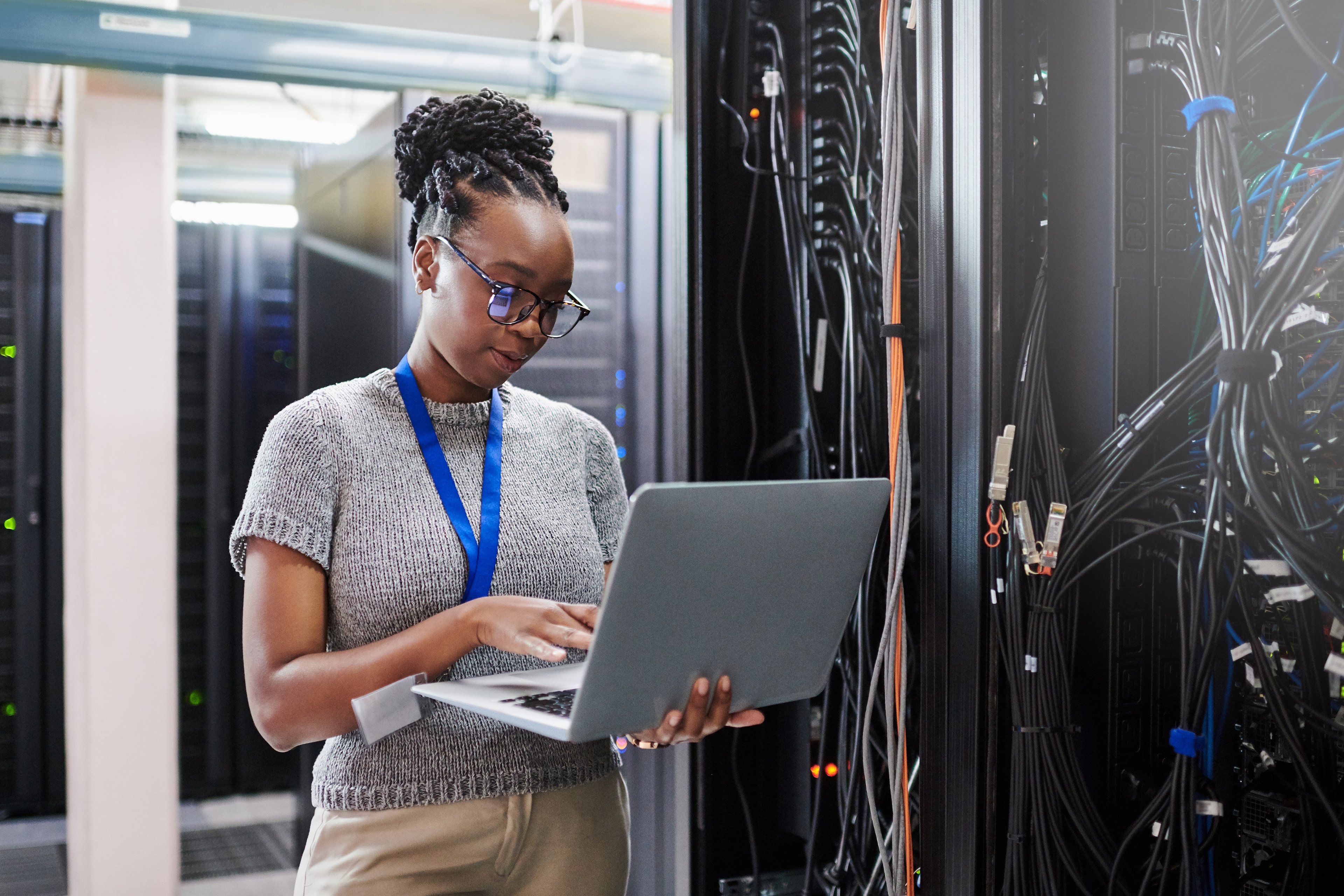 Person working on a laptop in a data center.