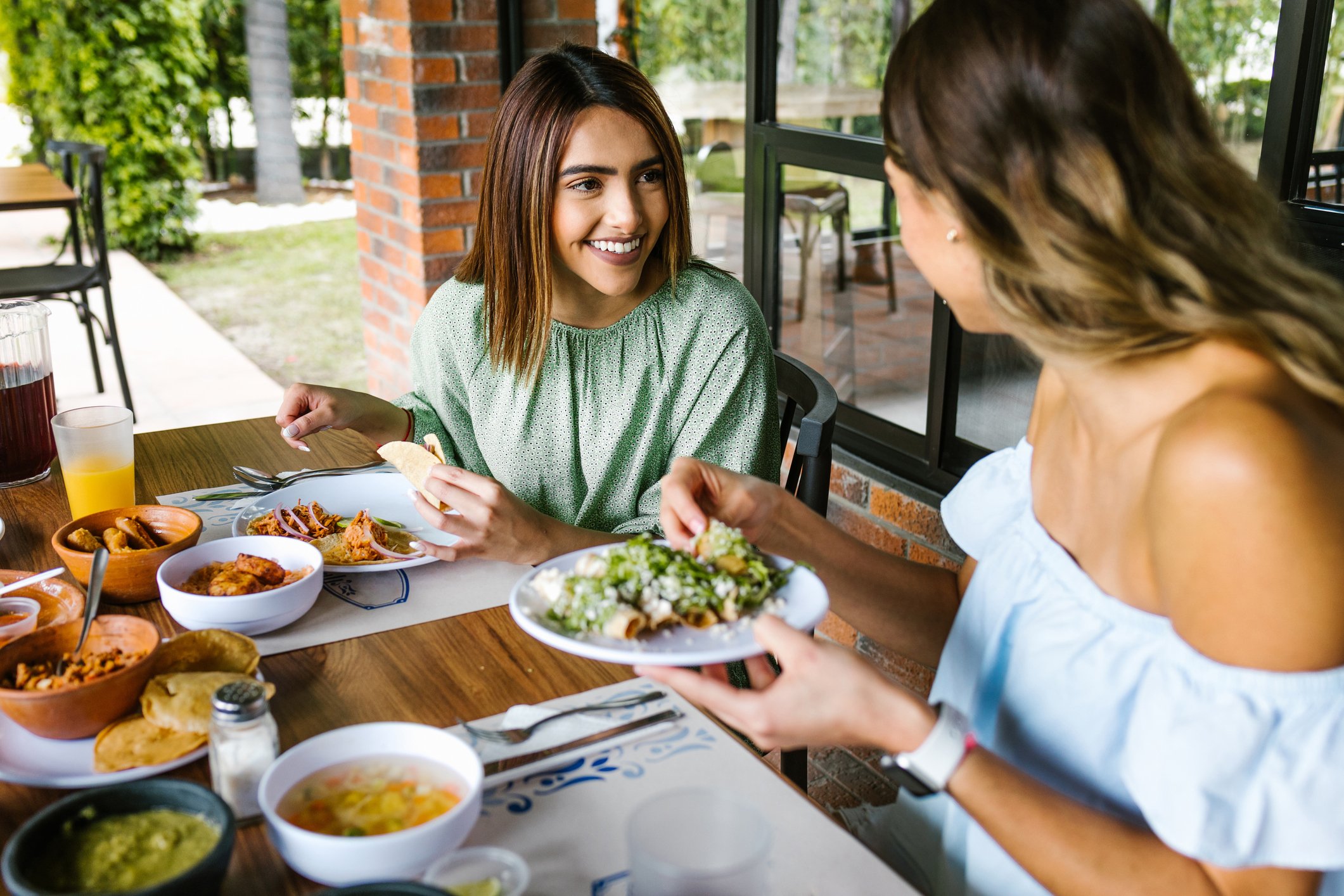 Two people eating outside at a restaurant.
