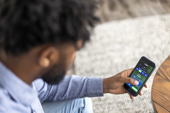 A person buys stock on a trading app on a mobile phone.