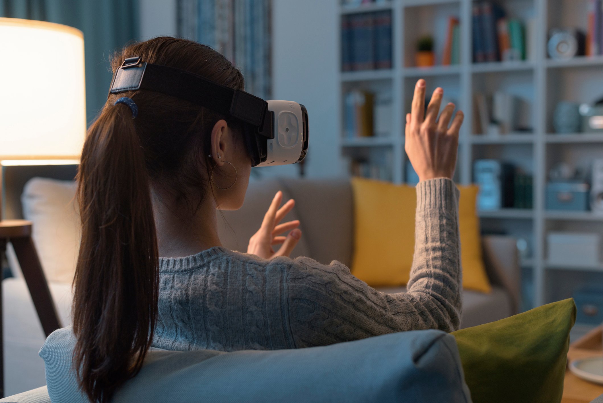 A person wears VR glasses at home to interact in a virtual world.
