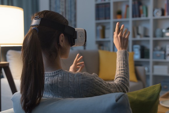 A person wears VR glasses at home to interact in a virtual world.