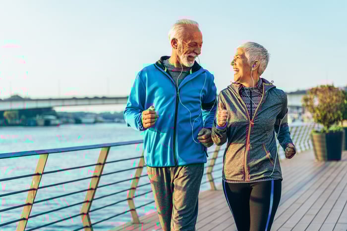 Two older people exercising outside.