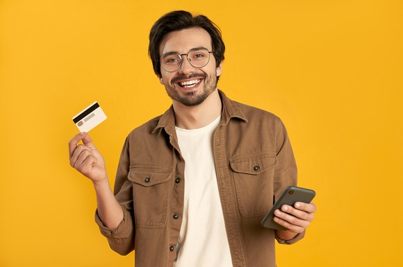 Person holding a credit card and their phone.
