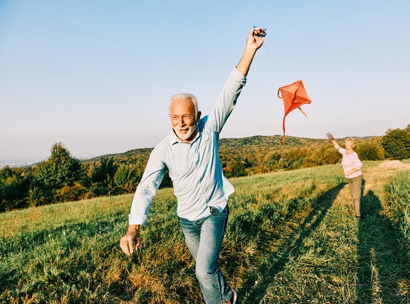 Elderly couple having fun and flying a kite.