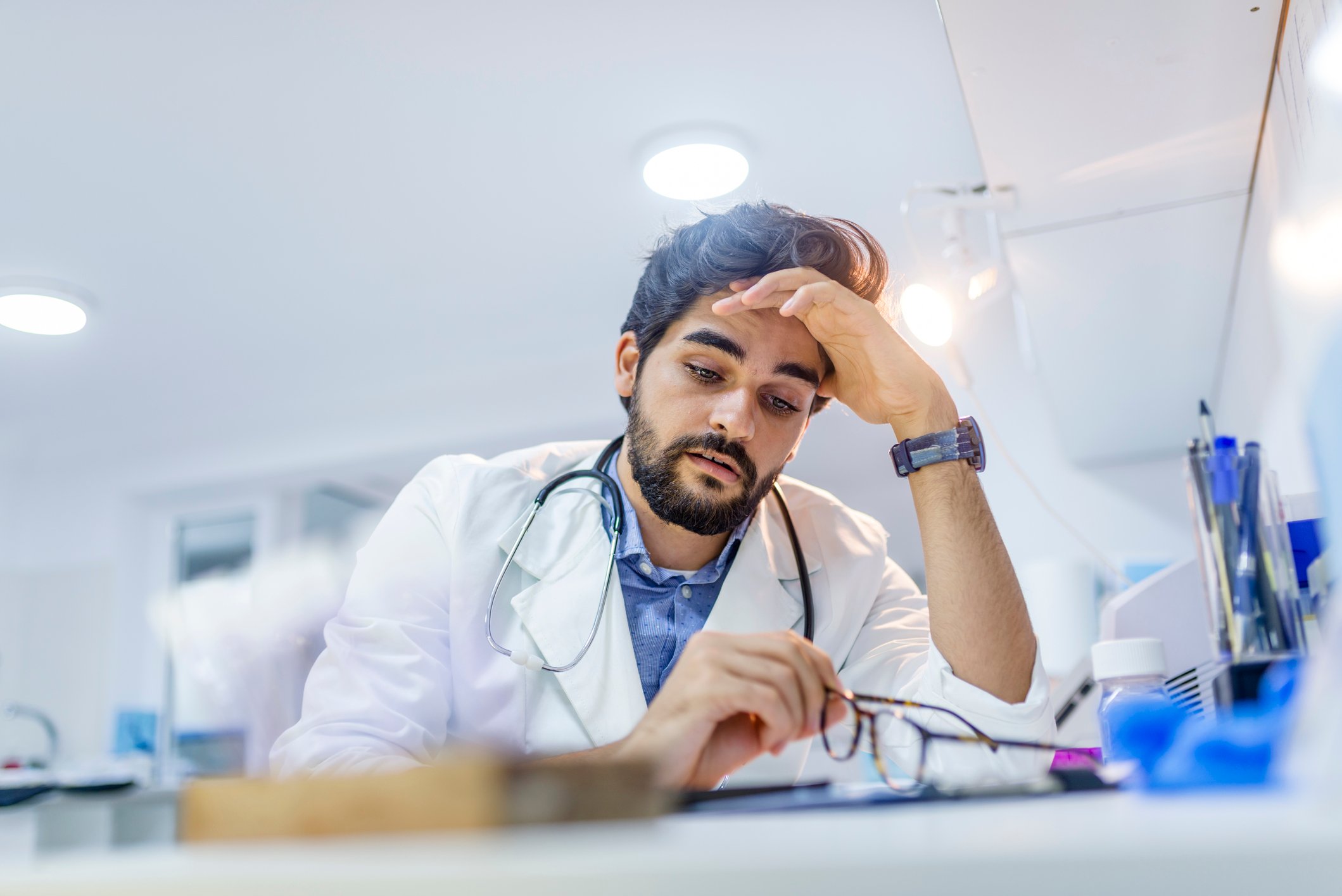 Medical professional seated and a desk and looking worried.