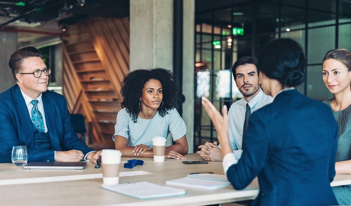 People in office at conference table during work meeting.