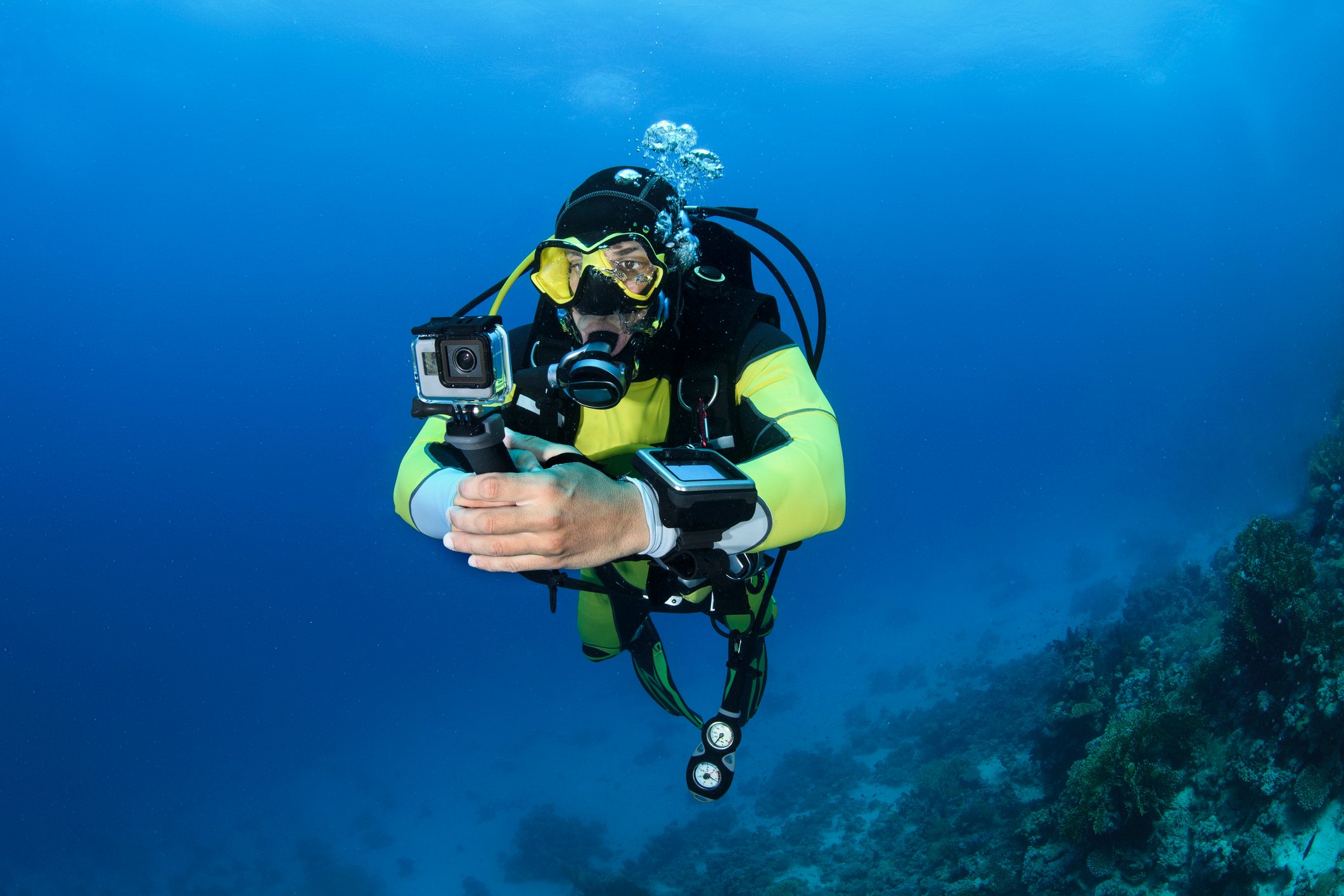 A scuba diver using a sports camera underwater.