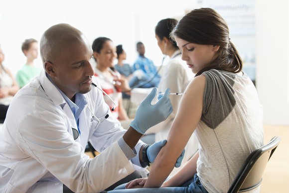 A healthcare professional is administering a vaccine to a patient. 