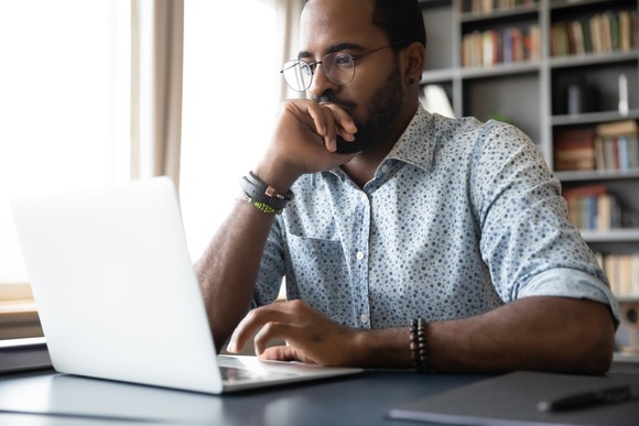 A person looks at a laptop in a home office.