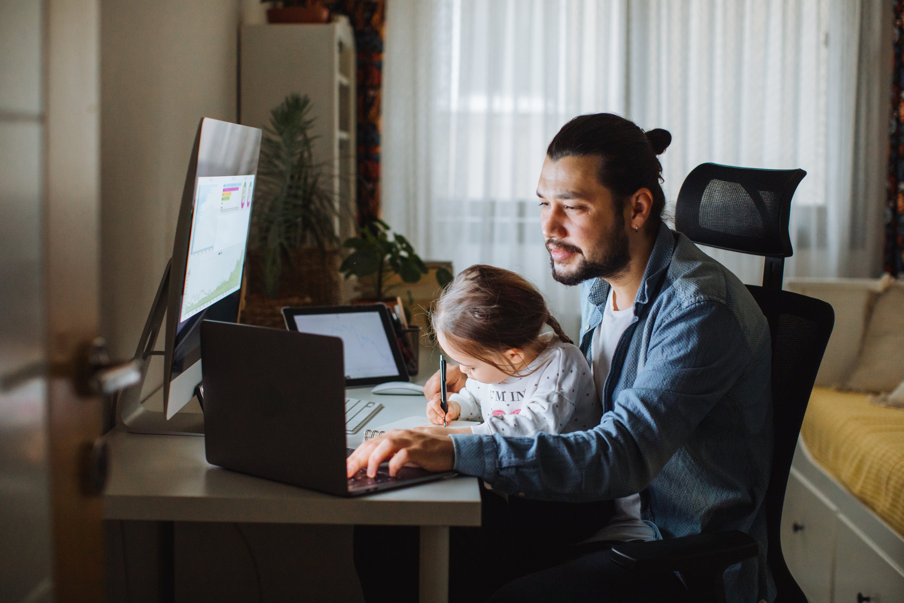 Person with child on lap looking at laptops.