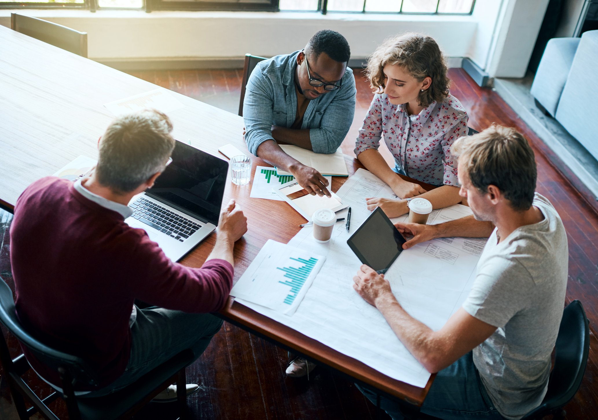 A group of employees sit around a table at a meeting.