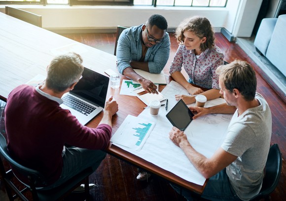 A group of employees sit around a table at a meeting.