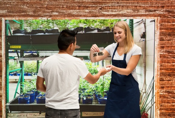 A worker helps a customer with a purchase at a cannabis dispensary.
