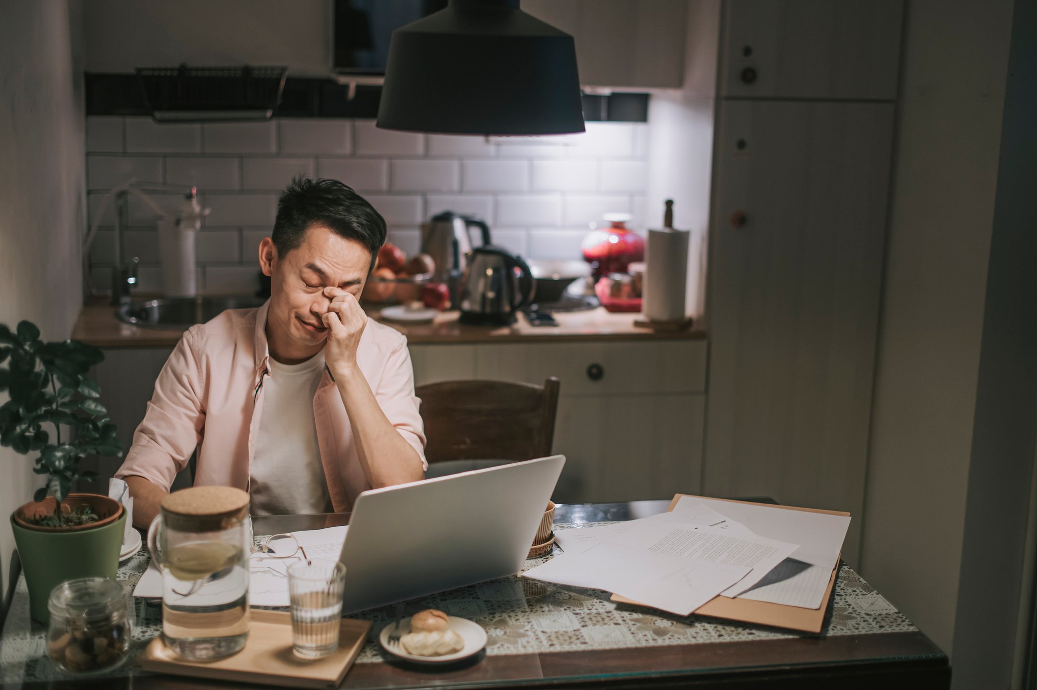 A person at their kitchen table, hand on face, looking nervous. 