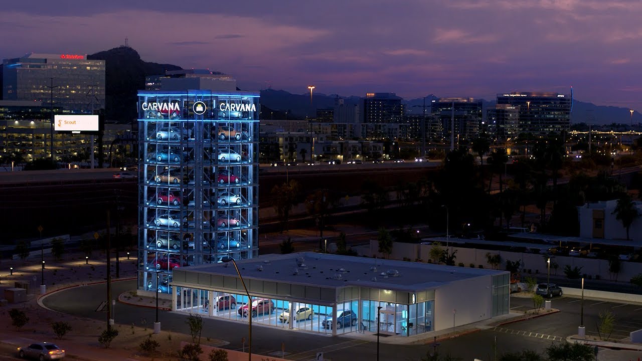 A Carvana vending machine tower against an urban backdrop. 