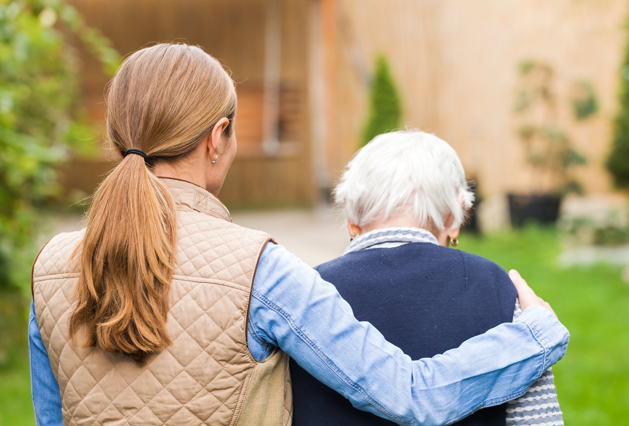 A healthcare worker walks with an elderly patient.