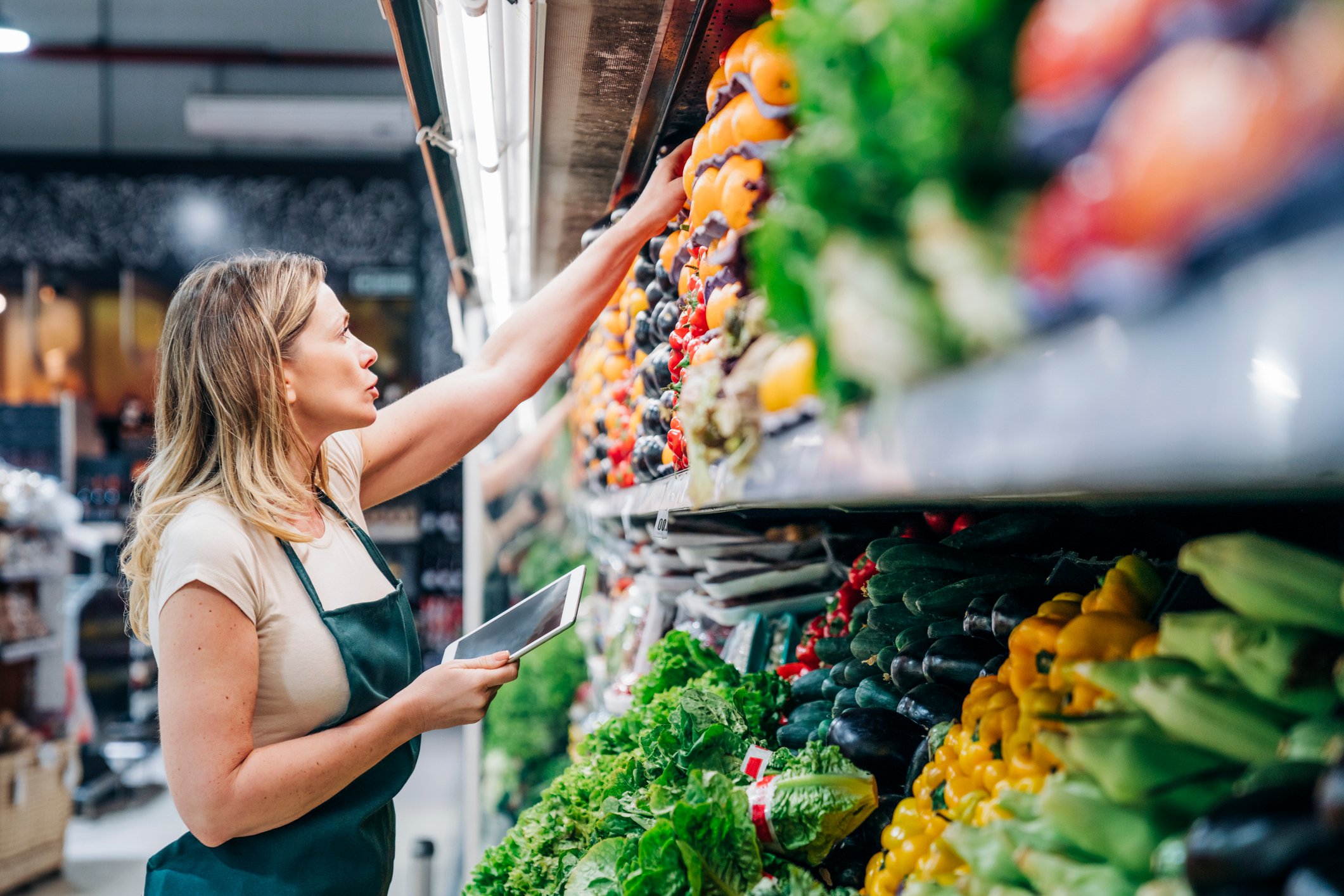 A person is inspecting vegetables inside a grocery store. 