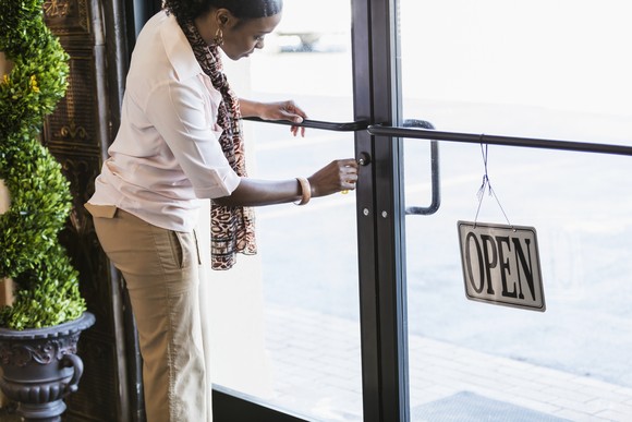 A person turns the key on the door to a retail store.