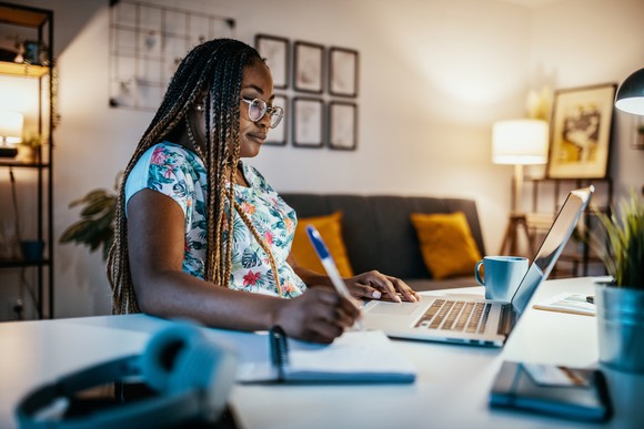 Woman learns via her laptop in her home. 