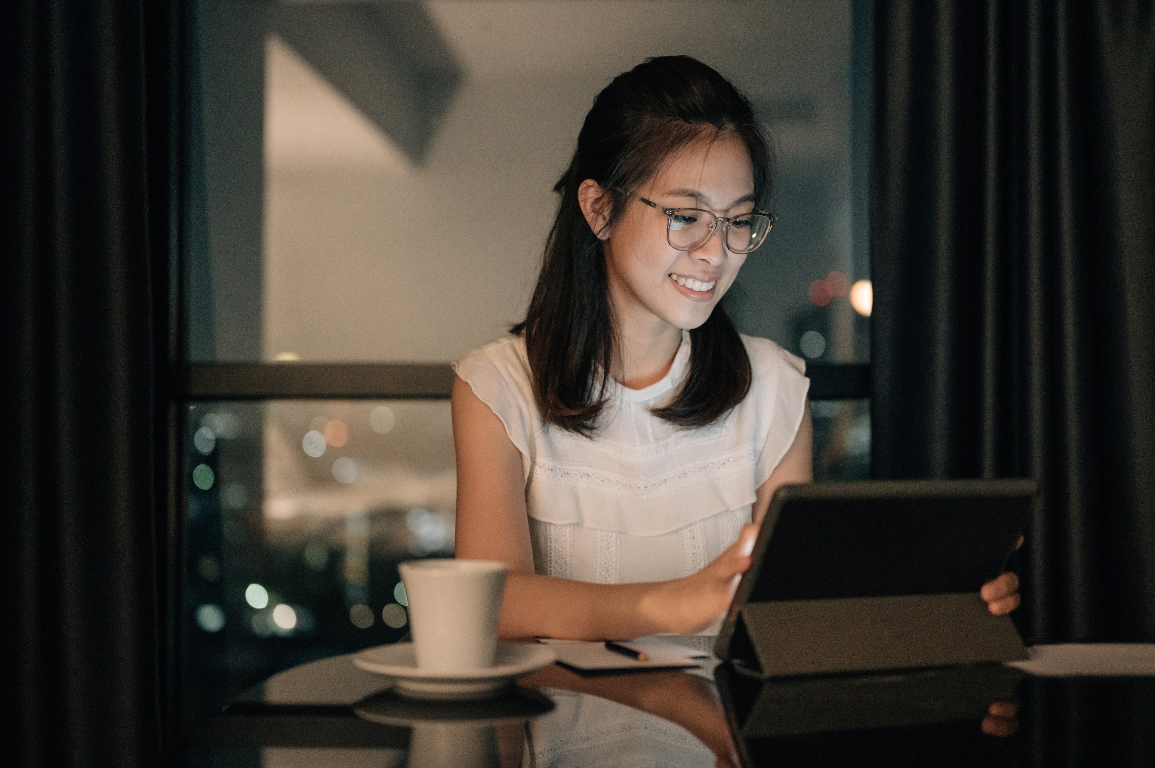 A smiling person typing on a tablet.