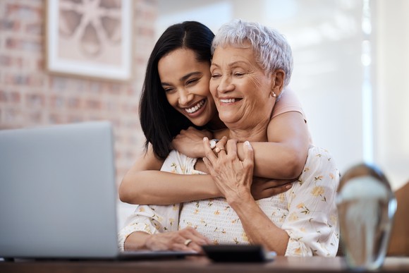Two people embrace while looking at a laptop.
