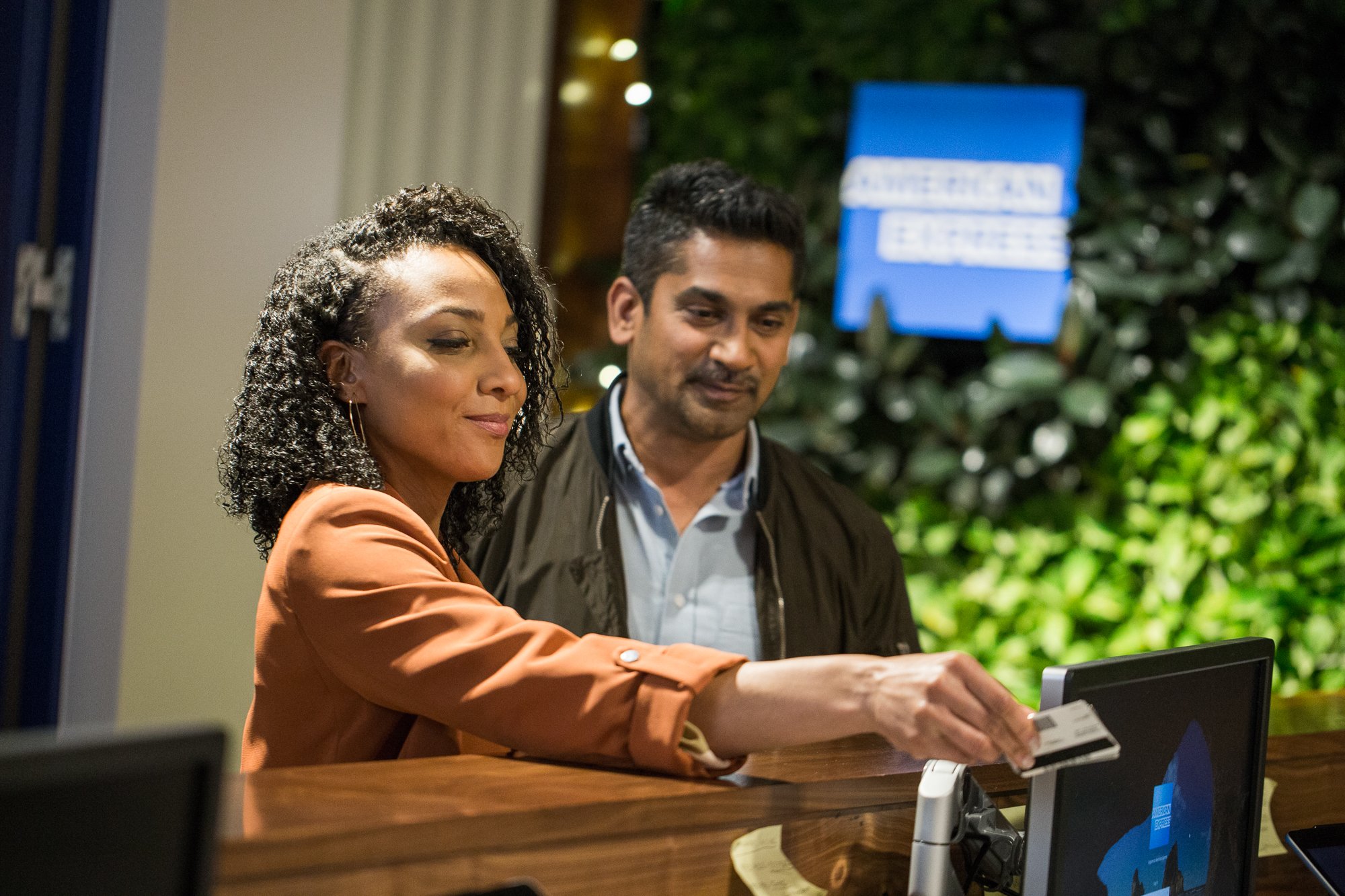 Two people checking into a hotel paying with a credit card.