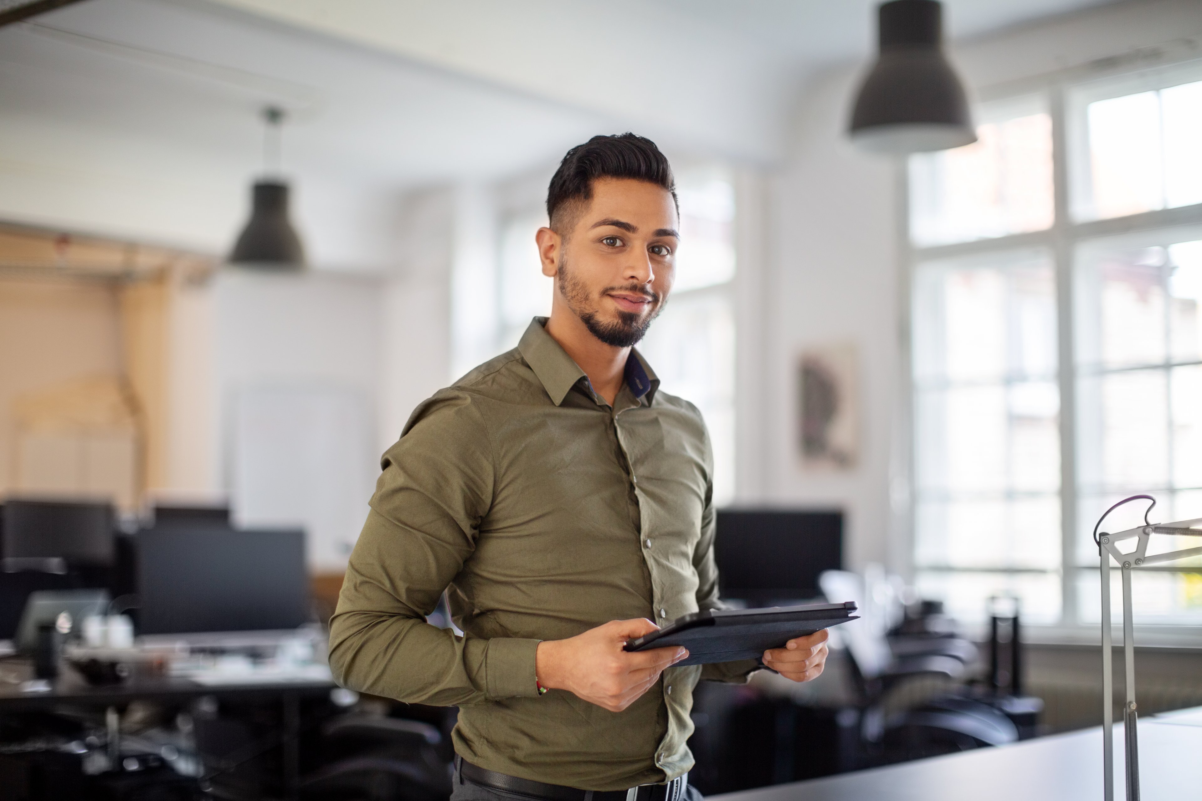 Person standing in office with digital tablet in hand