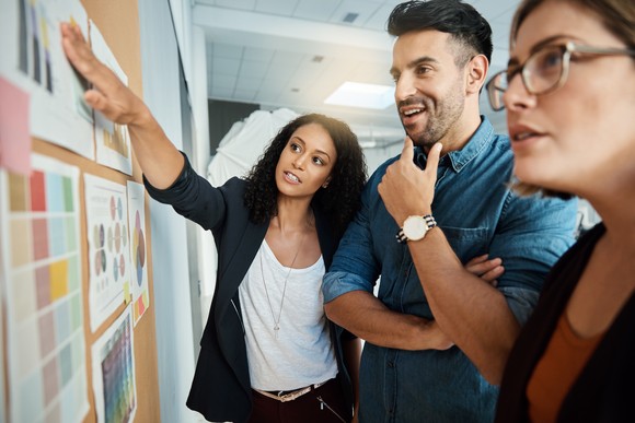 A group of colleagues having a brainstorming session around a bulletin board.