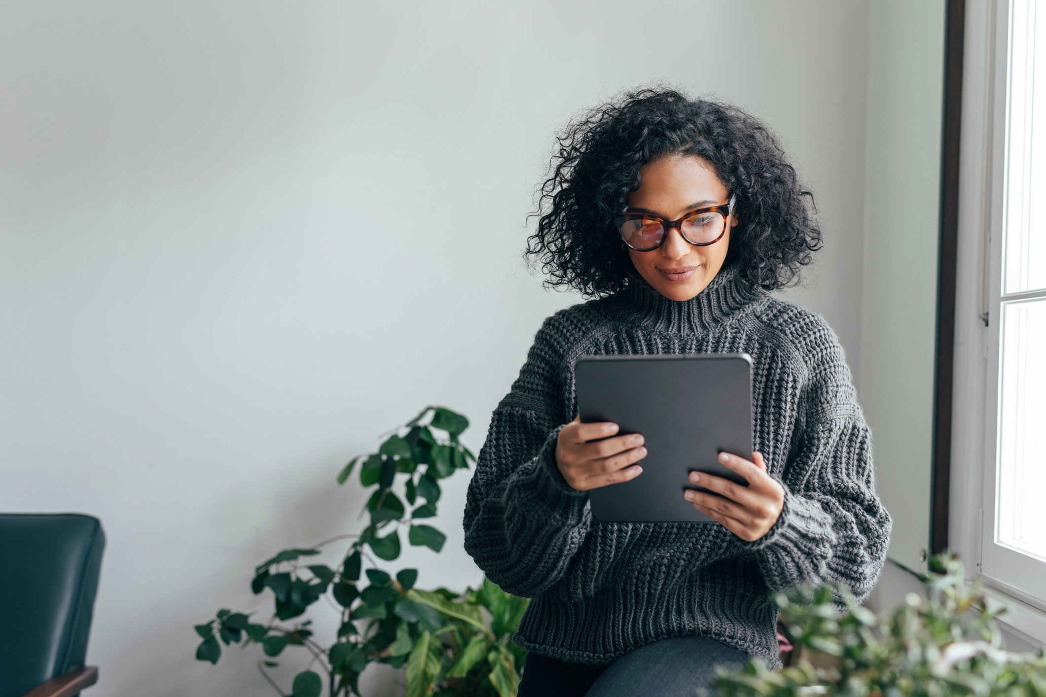 Person sitting inside looking at a tablet.