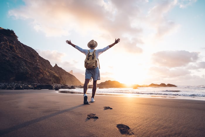 A person with outstretched arms facing the rising sun on the ocean. 