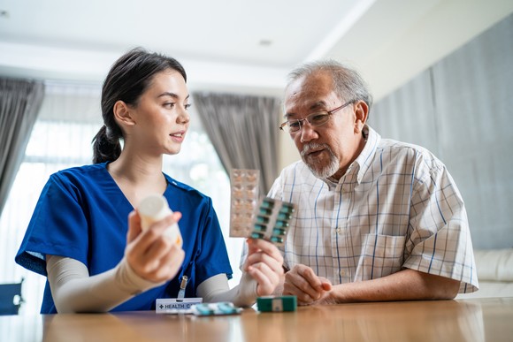 Healthcare worker showing prescription drugs to patient.