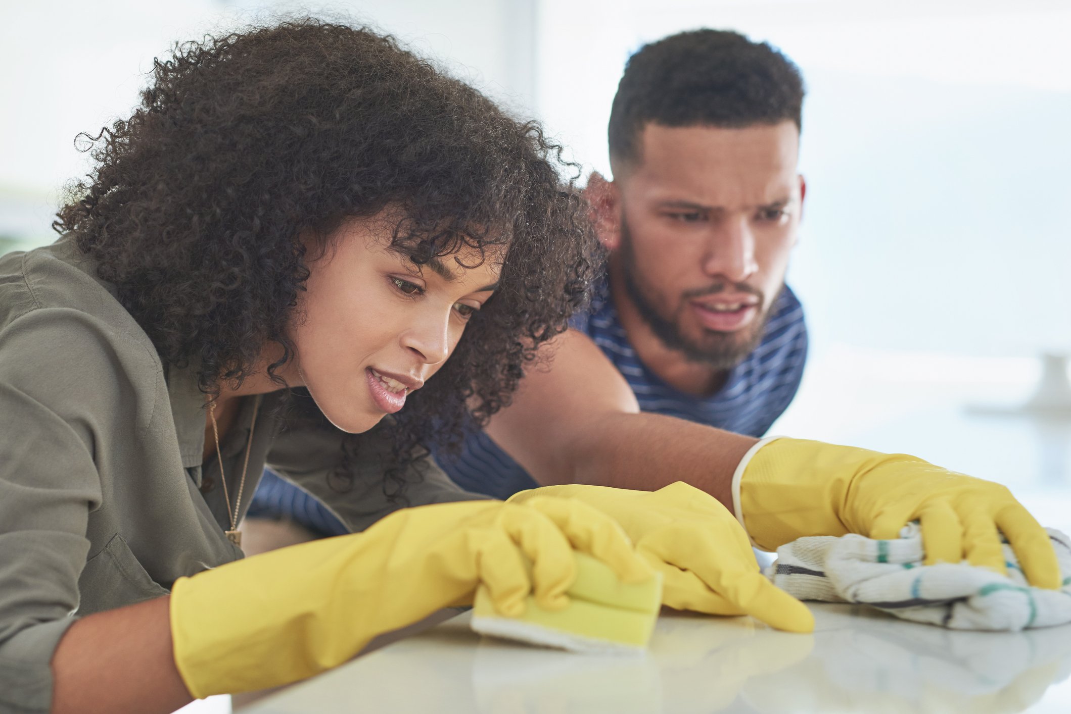 Two people working together to clean a countertop.