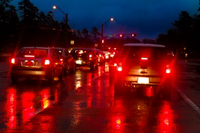 Cars with brake lights on at a stoplight at night.