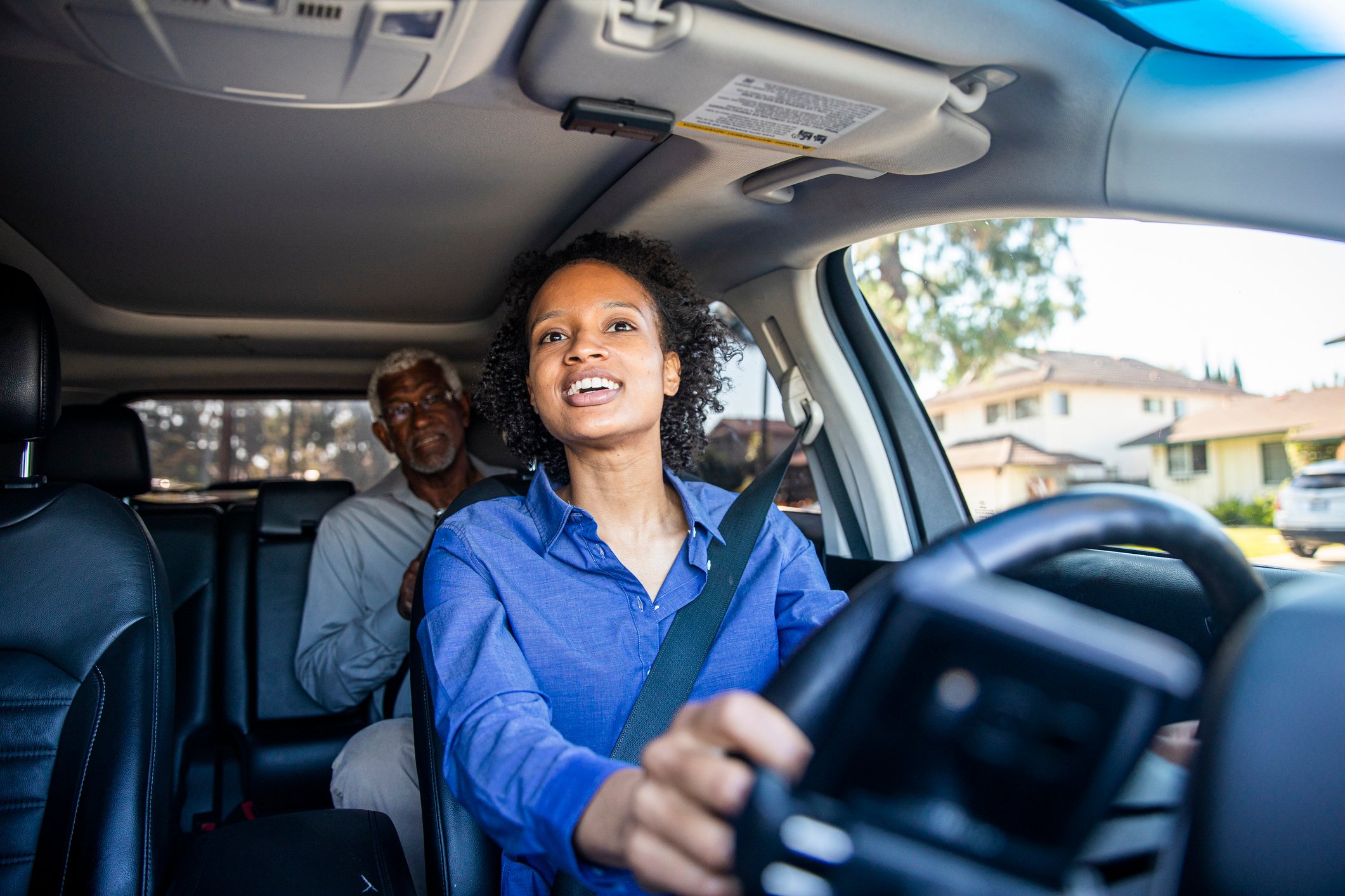 A car driver with a rider in the backseat. 