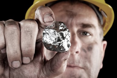 A miner holding a silver nugget.