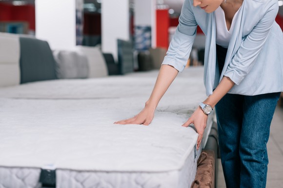 A person pressing on a mattress in a store.